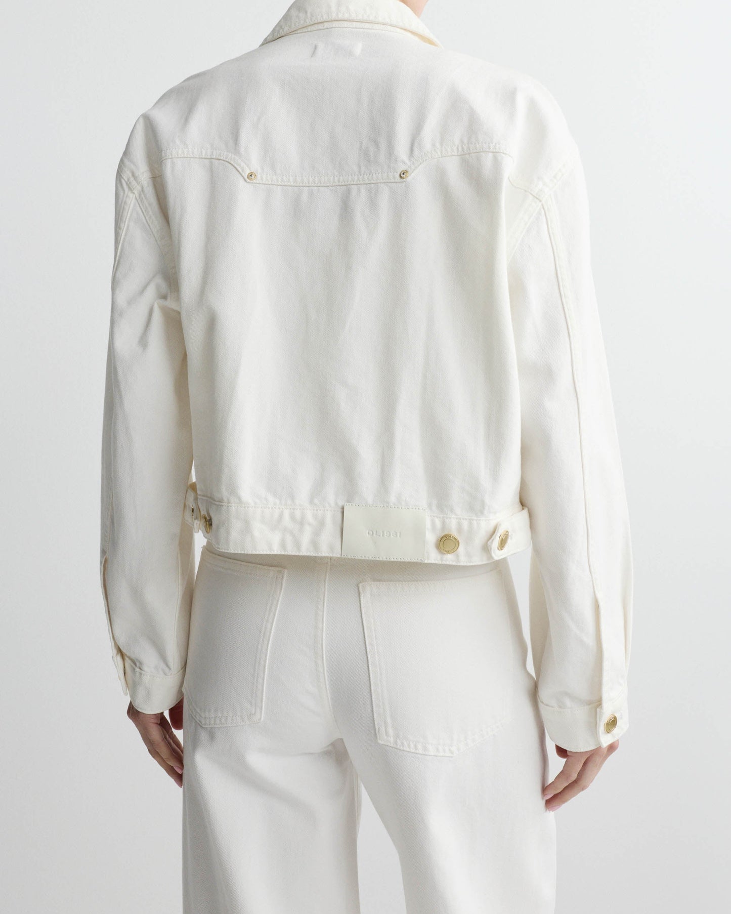White denim jacket worn by a person on a white background