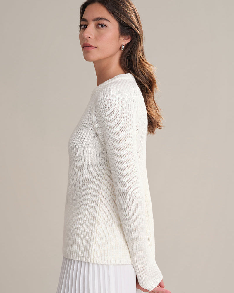 Woman wearing a white sweater against a plain background