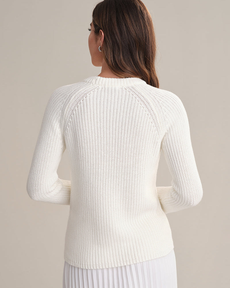 Woman wearing a white ribbed sweater against a plain background