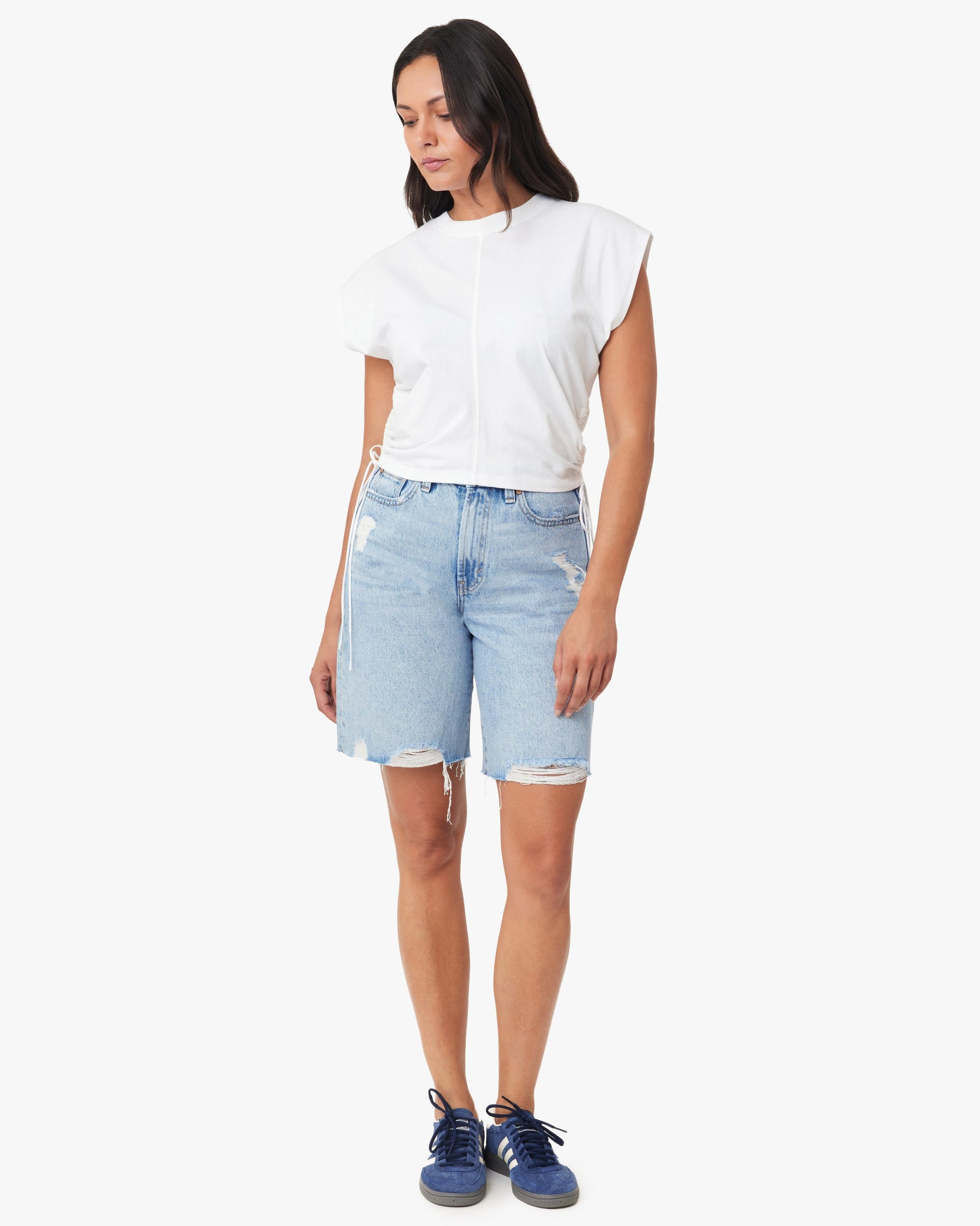 Woman wearing a white t-shirt and light blue denim shorts on a white background
