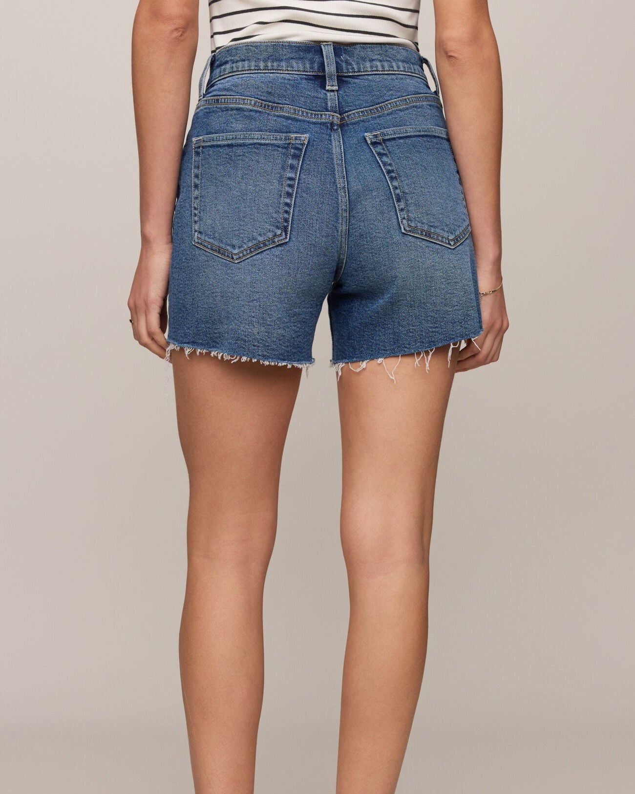 Person wearing blue denim shorts on a plain background