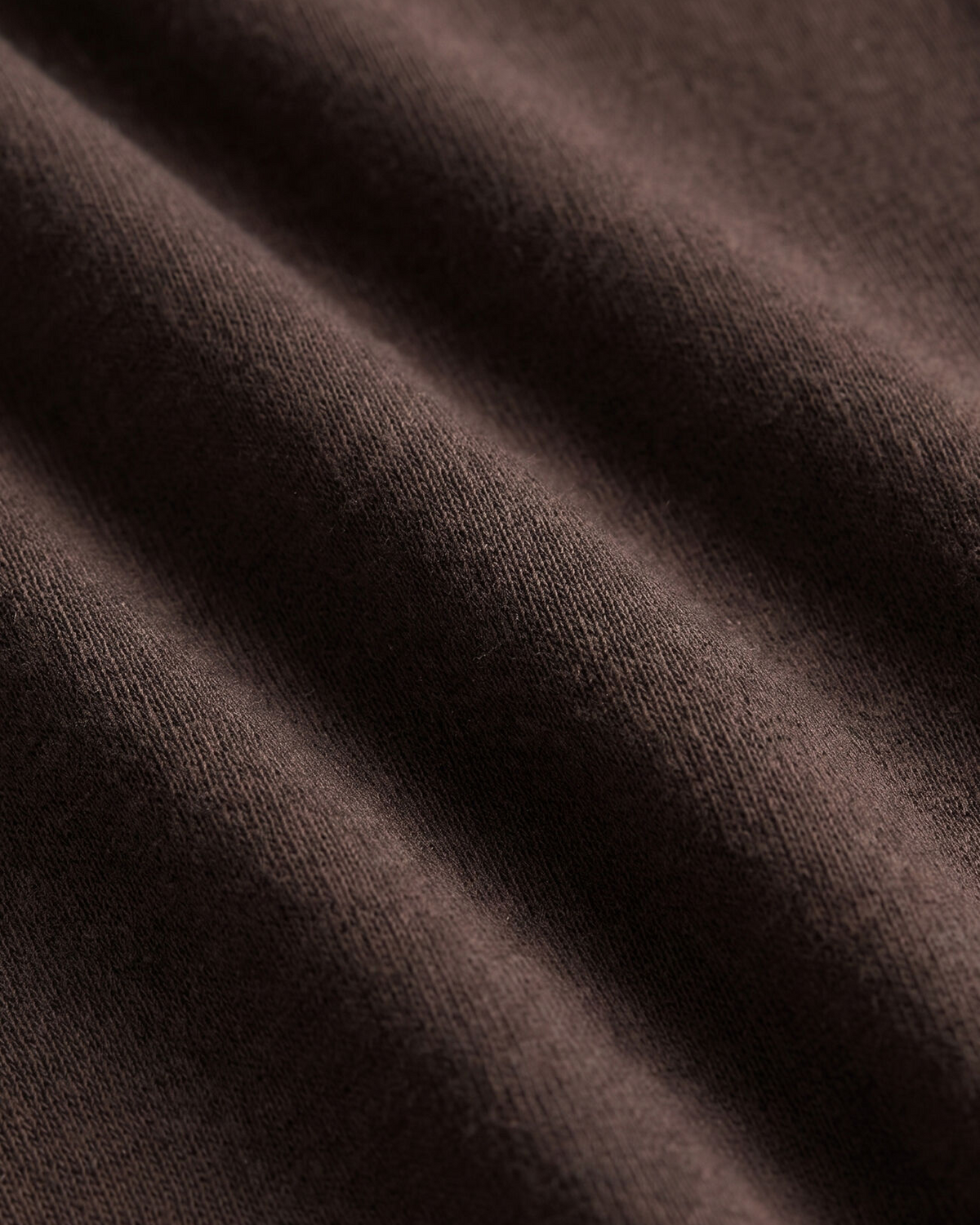 A close-up of draped dark brown knit fabric showing its soft texture and fine ribbed pattern.