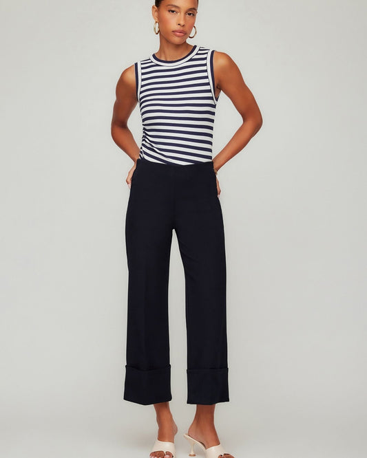 Woman wearing a striped sleeveless top and wide-leg pants on a plain background