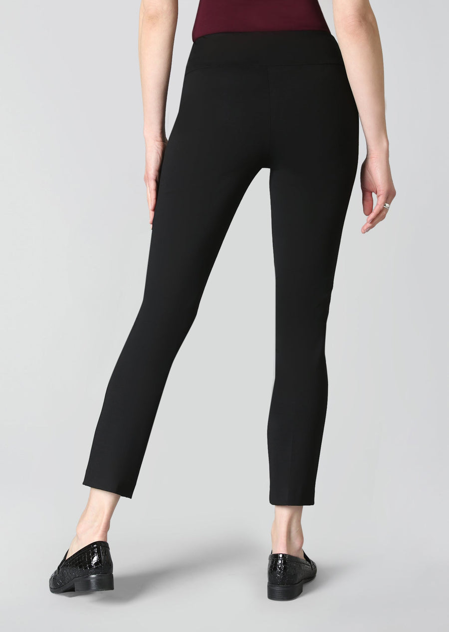A model from the waist down wearing black cropped leggings and black patent leather loafers, photographed against a solid light gray studio background.