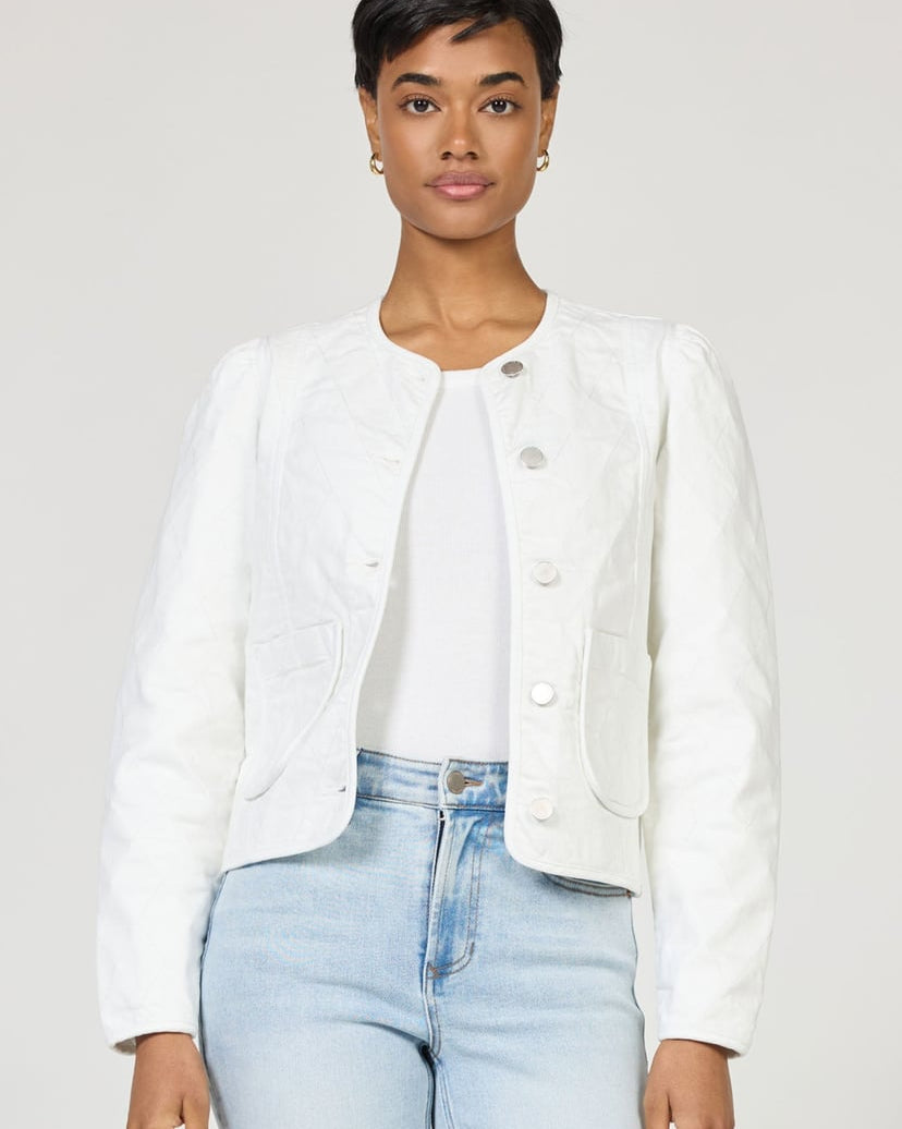 Person wearing a white jacket and light blue jeans on a plain background