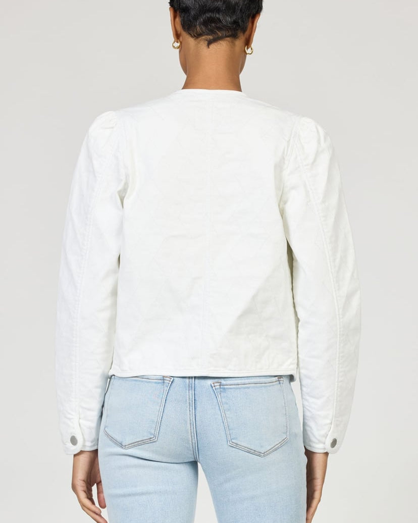 Person wearing a white long-sleeve shirt and light blue jeans on a plain background