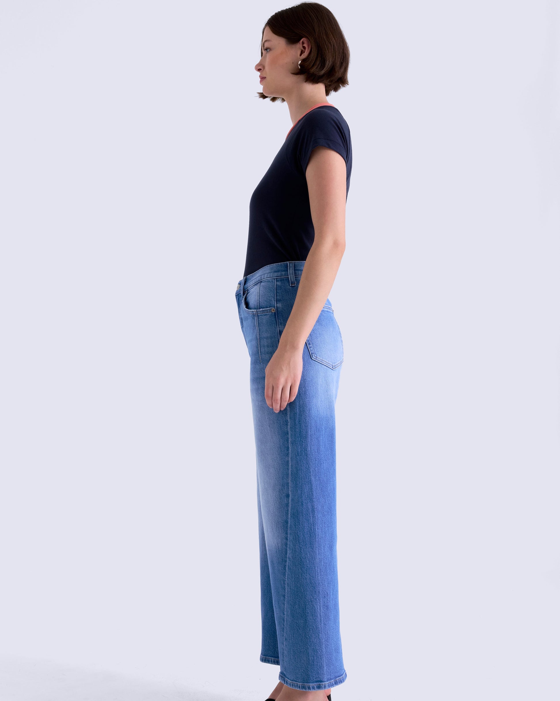 Person wearing a black top and light blue jeans on a white background