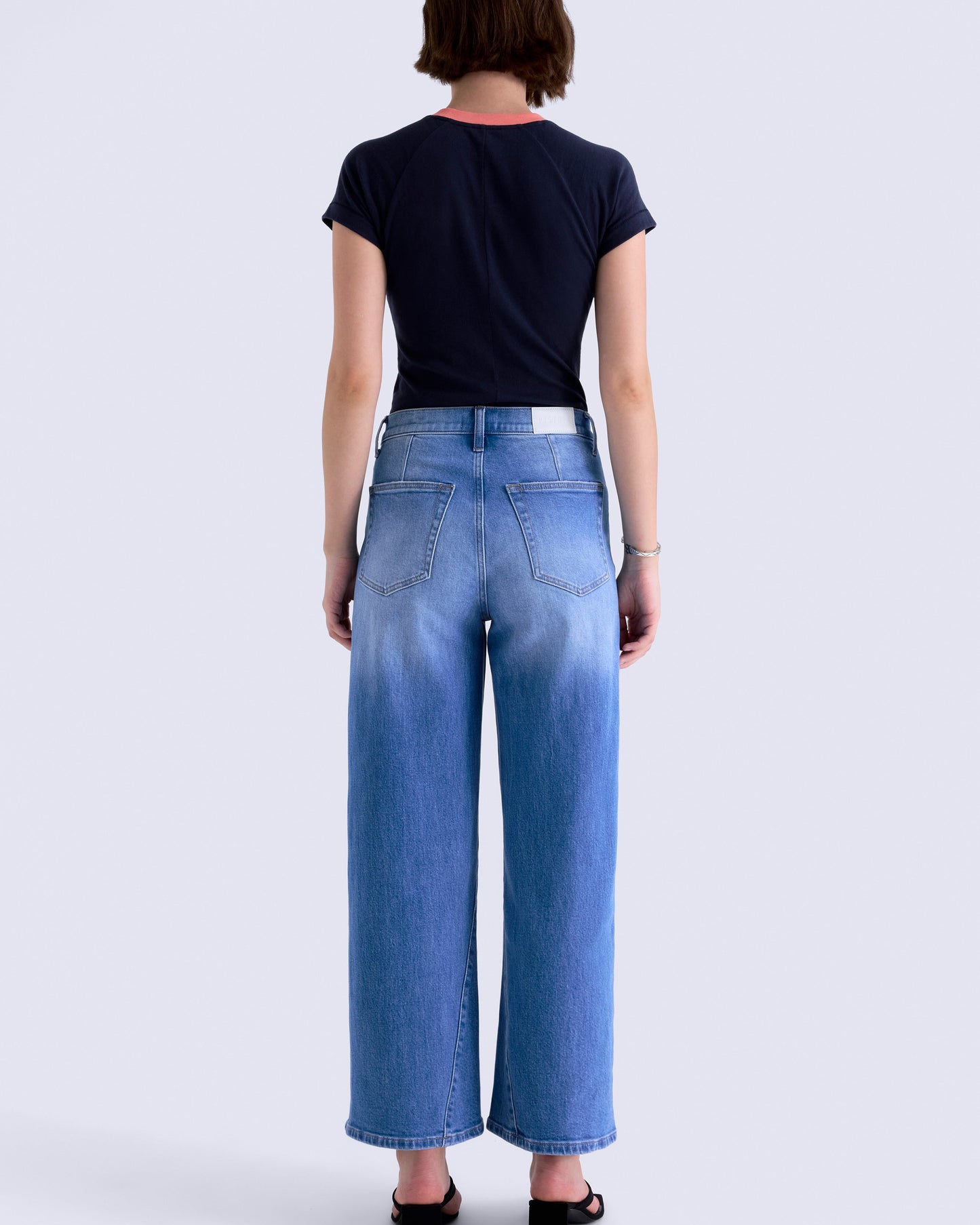 Person wearing blue jeans and a black shirt on a white background