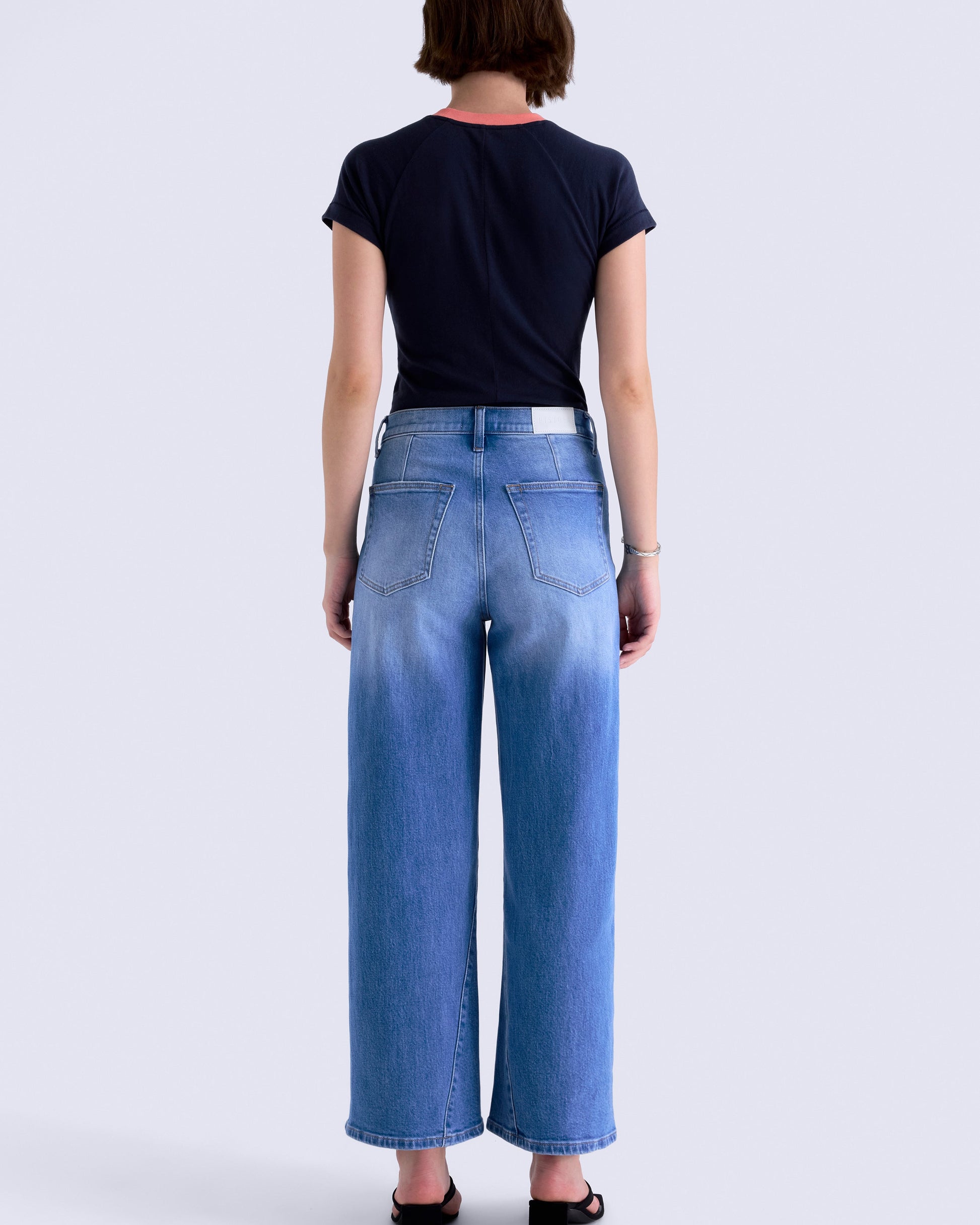 Person wearing blue jeans and a black shirt on a white background