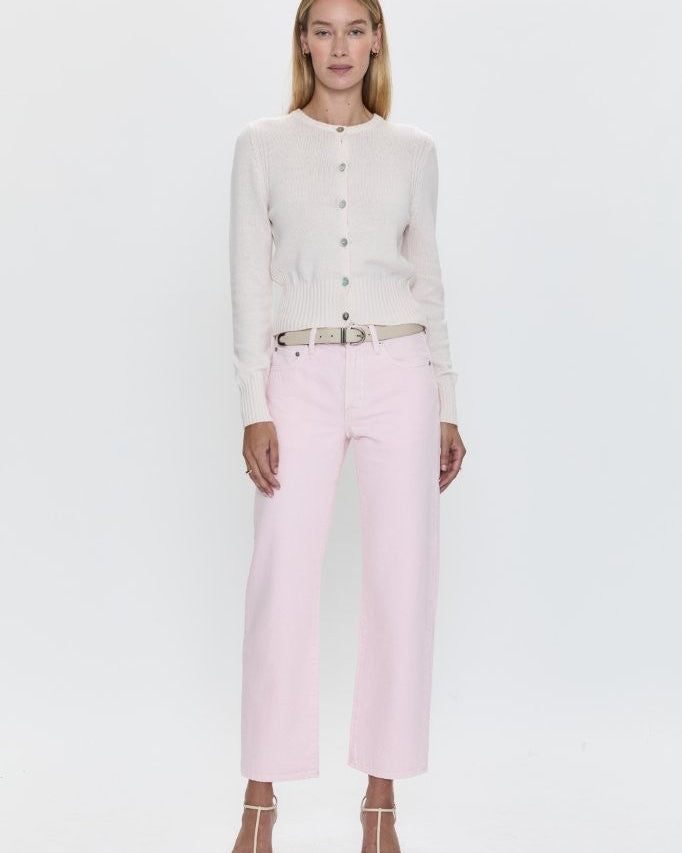 model wearing pink jeans and white cardigan standing in front of a white background