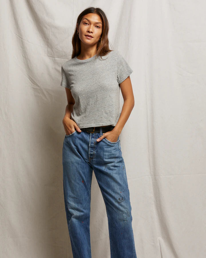 Person wearing a gray t-shirt and blue jeans against a plain background