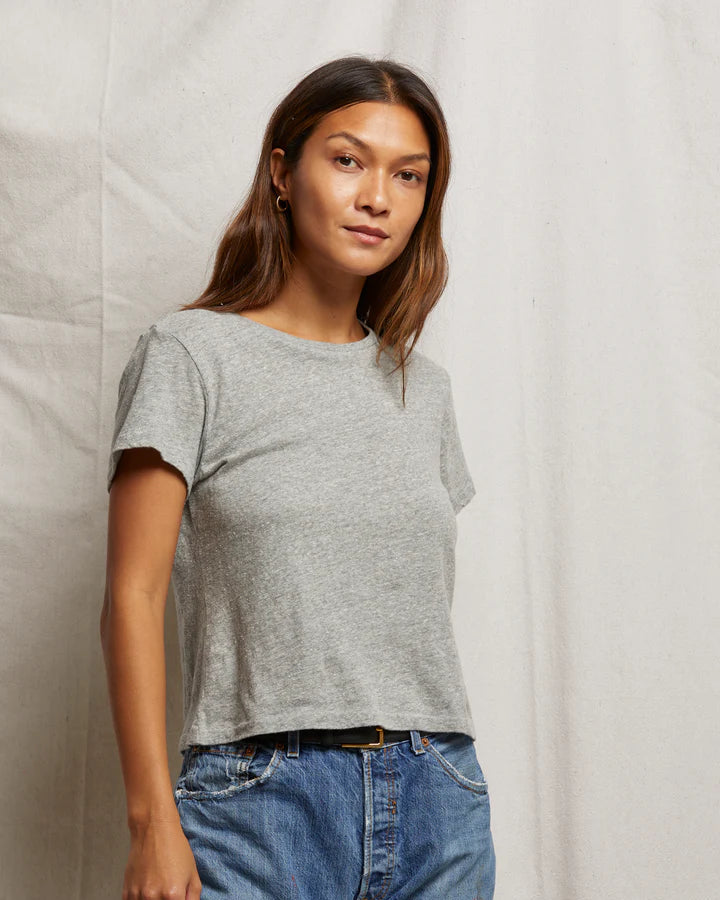 Person wearing a gray t-shirt and blue jeans against a neutral background