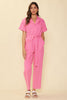 Model Wearing Skies Are Blue Pink Denim Utility Jumpsuit On A Yellow Background