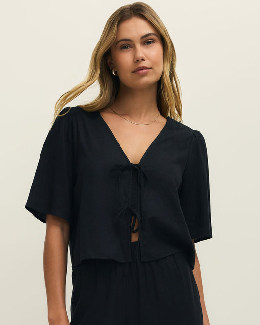 Woman wearing a black outfit against a beige background