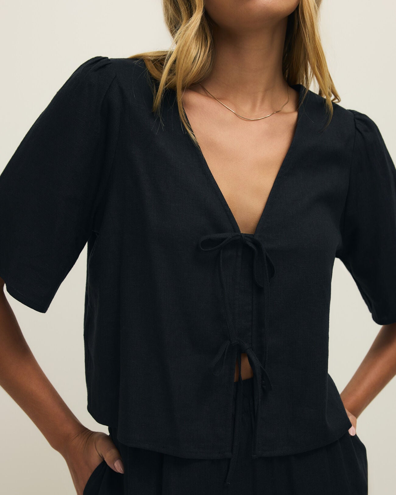 Person wearing a black outfit with a plunging neckline against a neutral background