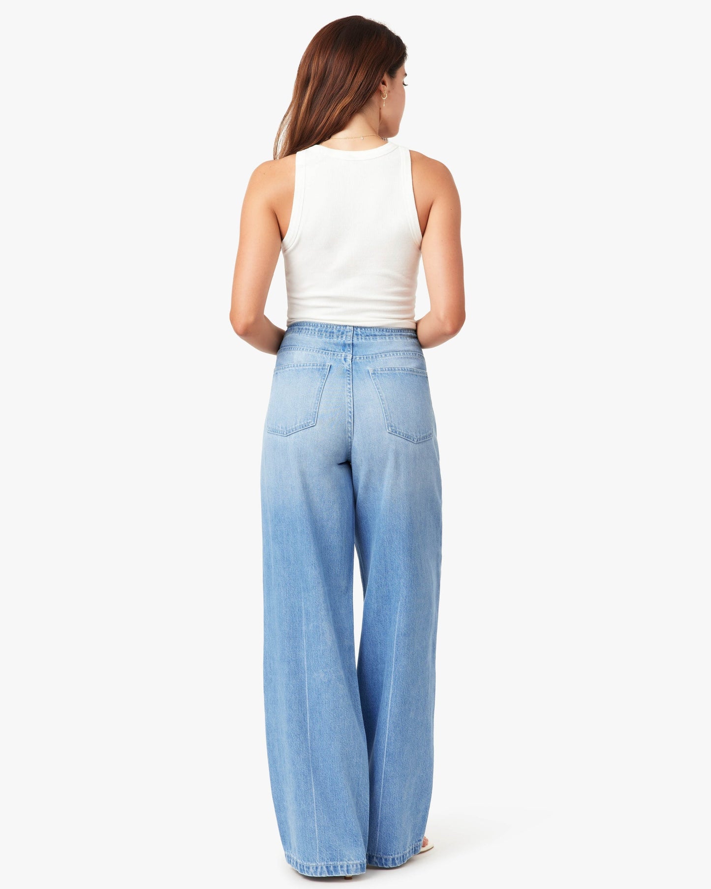 Woman wearing light blue jeans and a white top on a white background