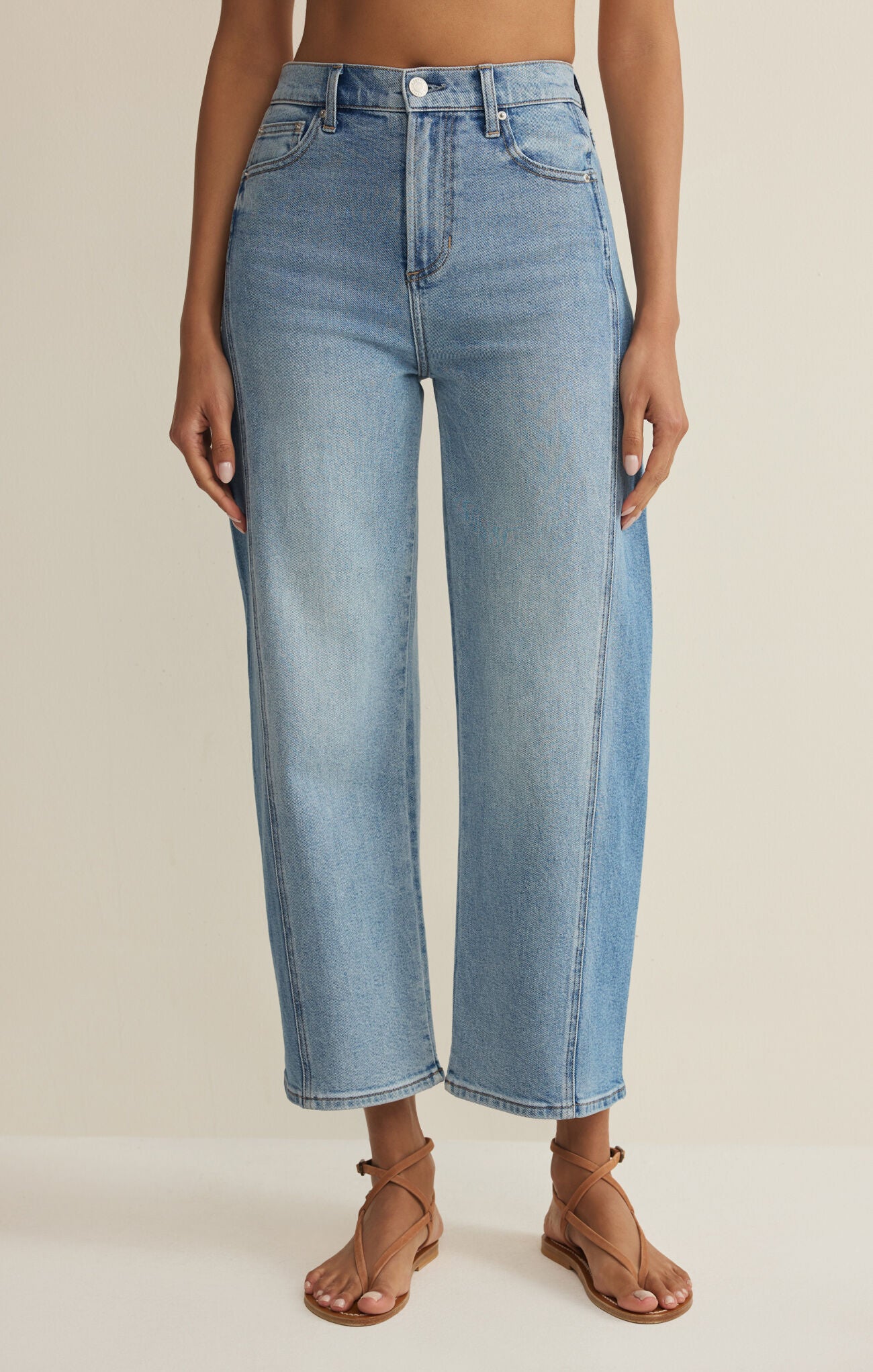 Light blue jeans worn by a person on a beige background