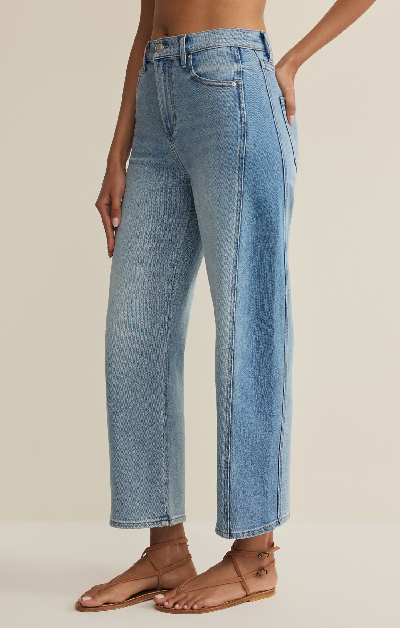 Light blue jeans worn by a person on a beige background