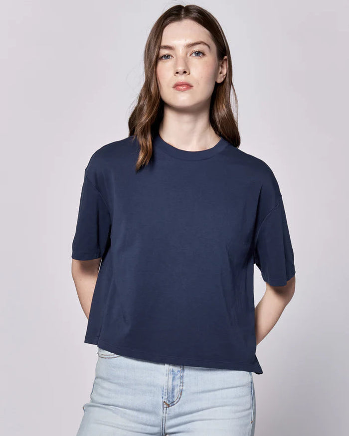 Person wearing a navy blue t-shirt and light blue jeans on a plain background