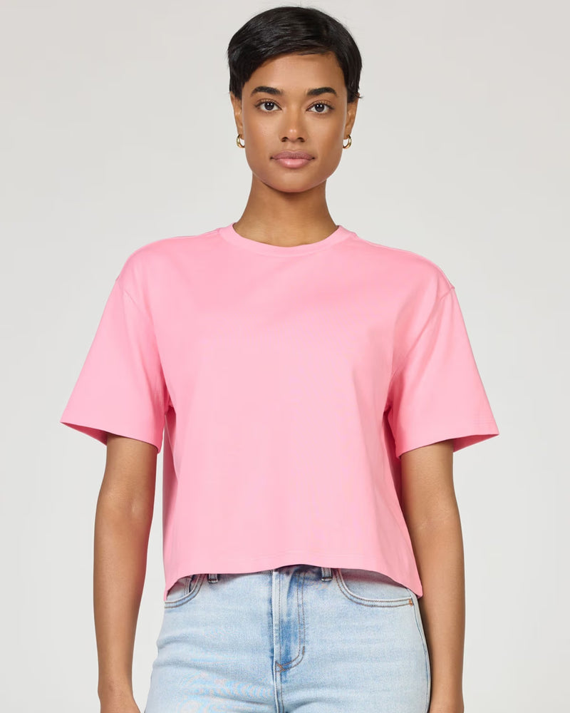 Person wearing a pink t-shirt and light blue jeans on a plain background