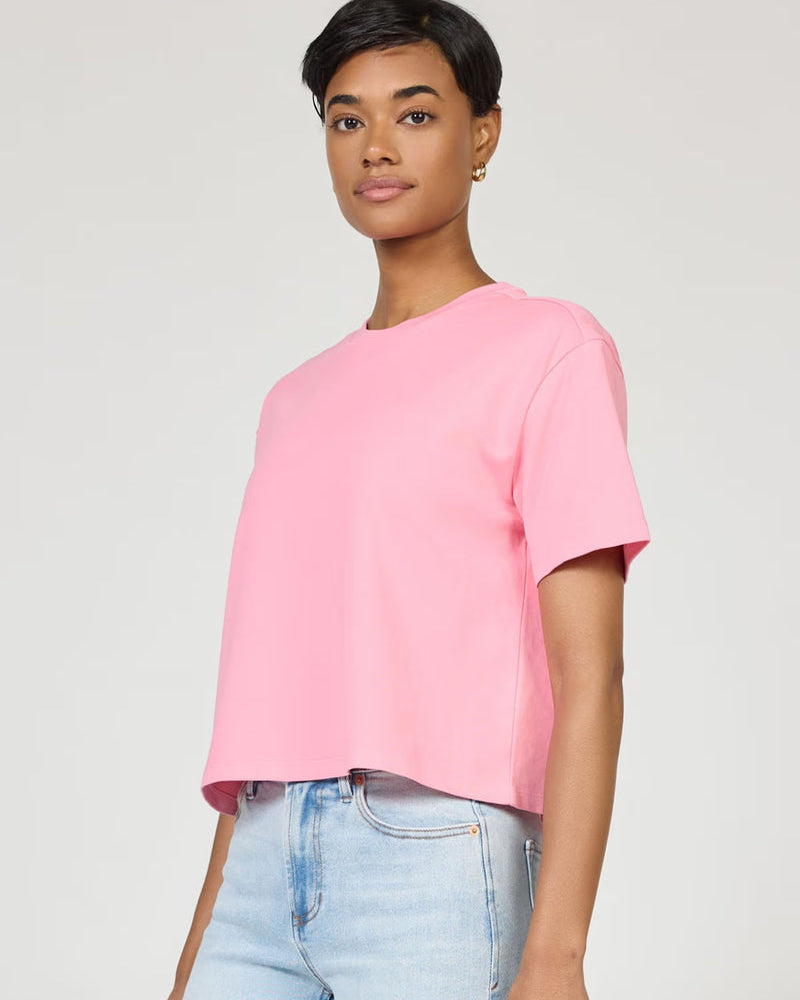 Woman wearing a pink t-shirt and light blue jeans against a plain background