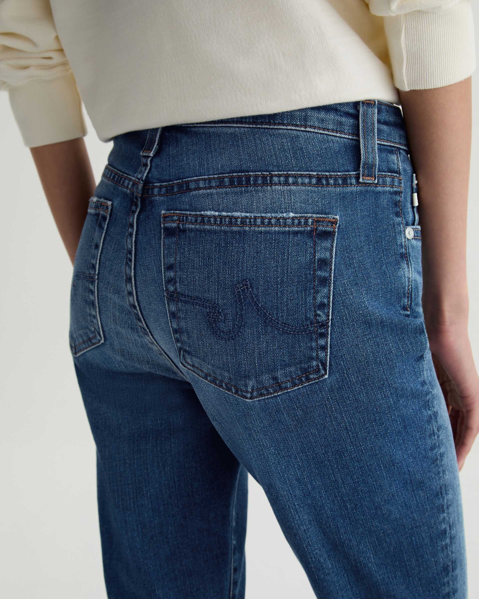Person wearing blue jeans with a neutral background