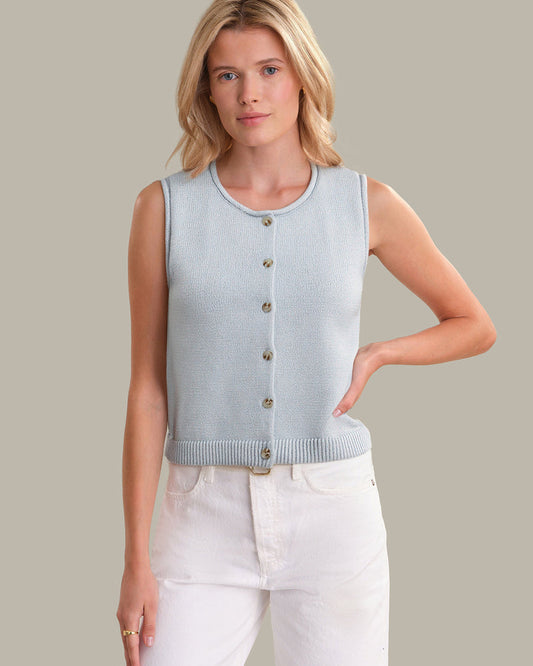 Woman wearing a light blue sleeveless cardigan with buttons on a plain background