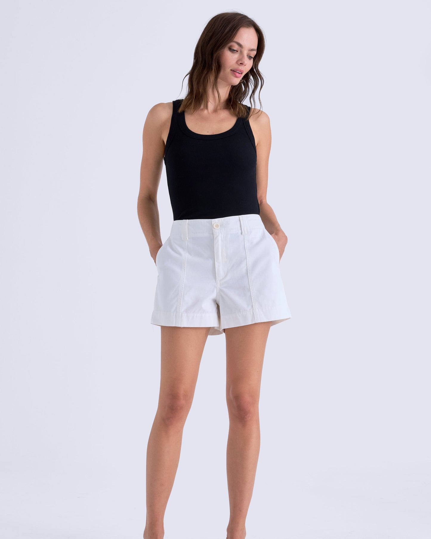 Woman wearing a black tank top and white shorts on a white background