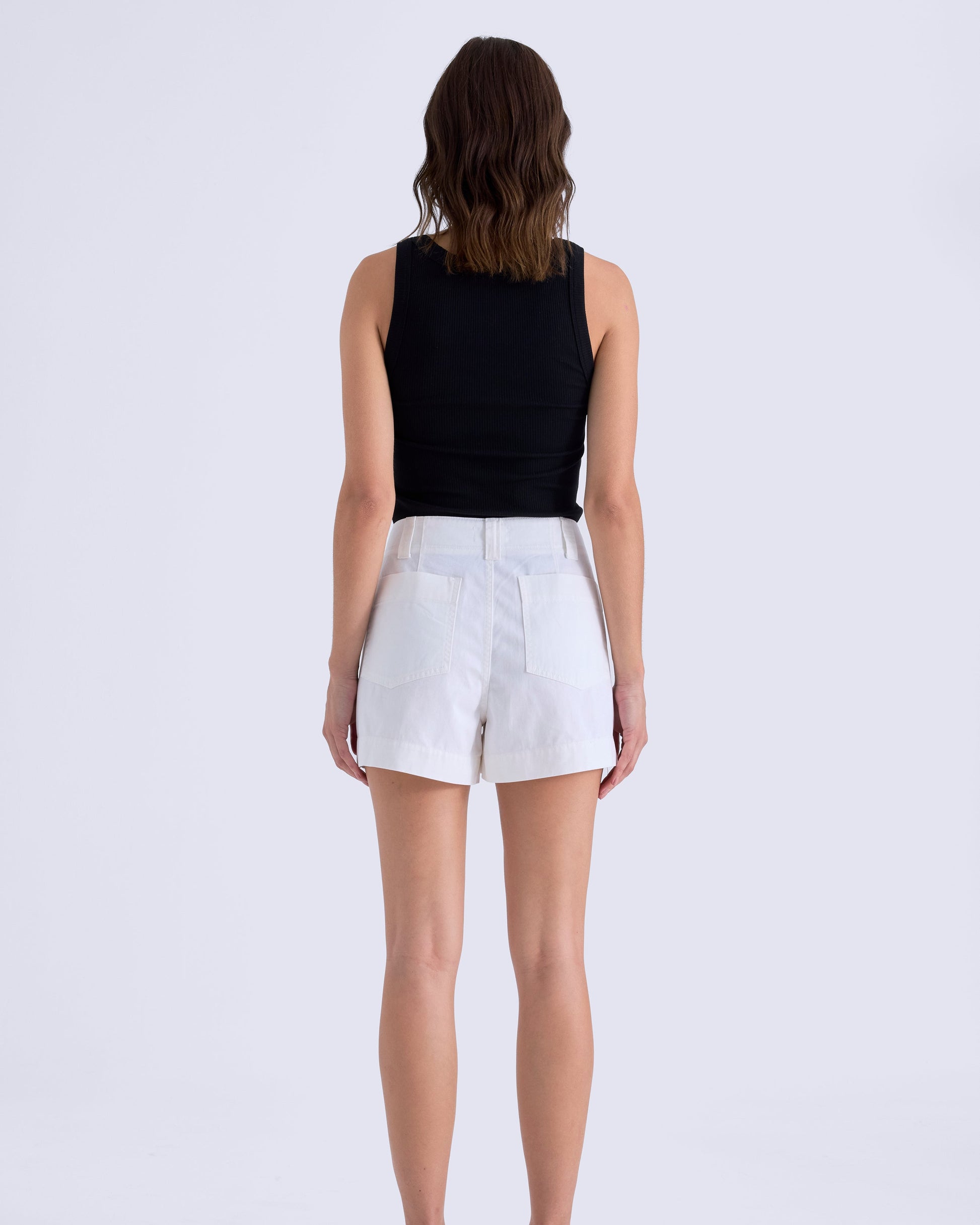 Person wearing a black sleeveless top and white shorts on a white background