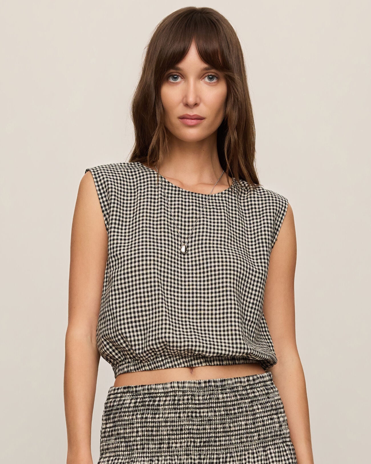 Woman wearing a black and white checkered top and skirt on a beige background