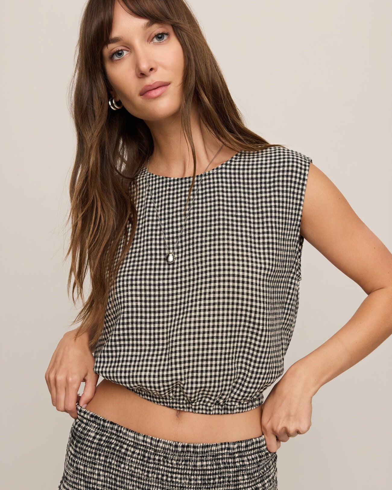 Woman wearing a black and white checkered top and skirt on a beige background