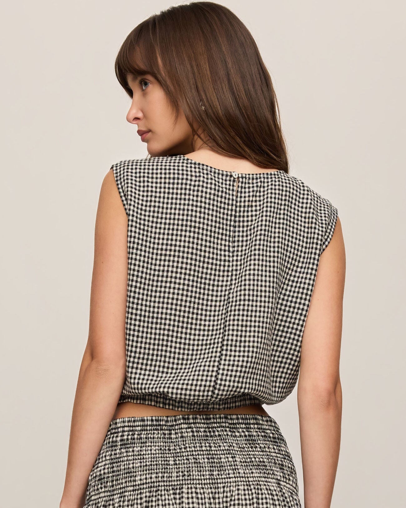 Woman wearing a black and white checkered dress against a beige background