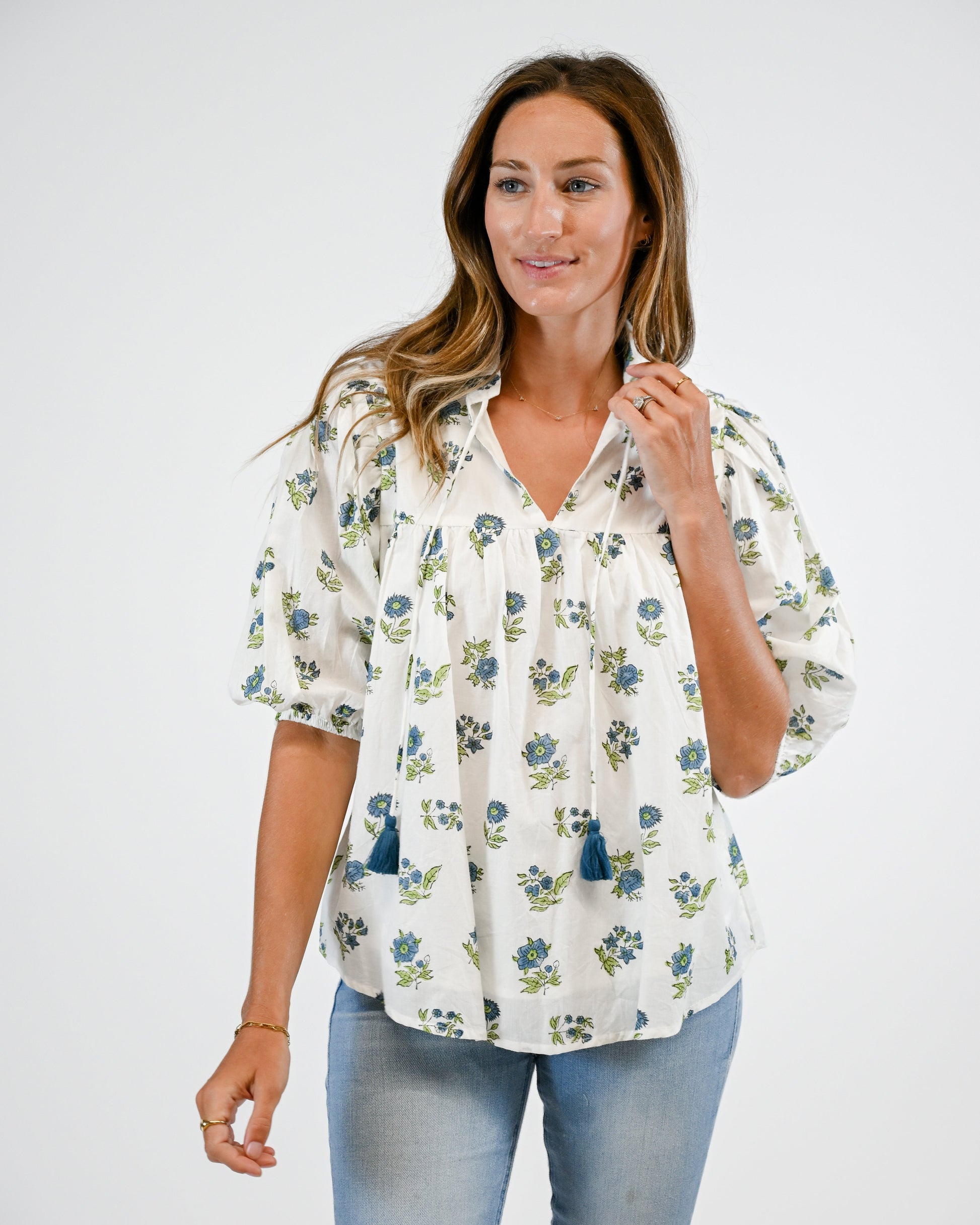 Woman wearing a floral blouse and light blue jeans on a white background