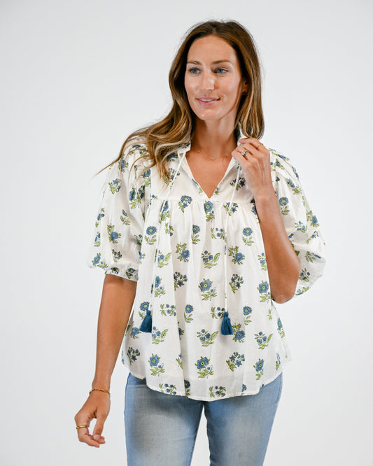 Woman wearing a floral blouse and light blue jeans on a white background