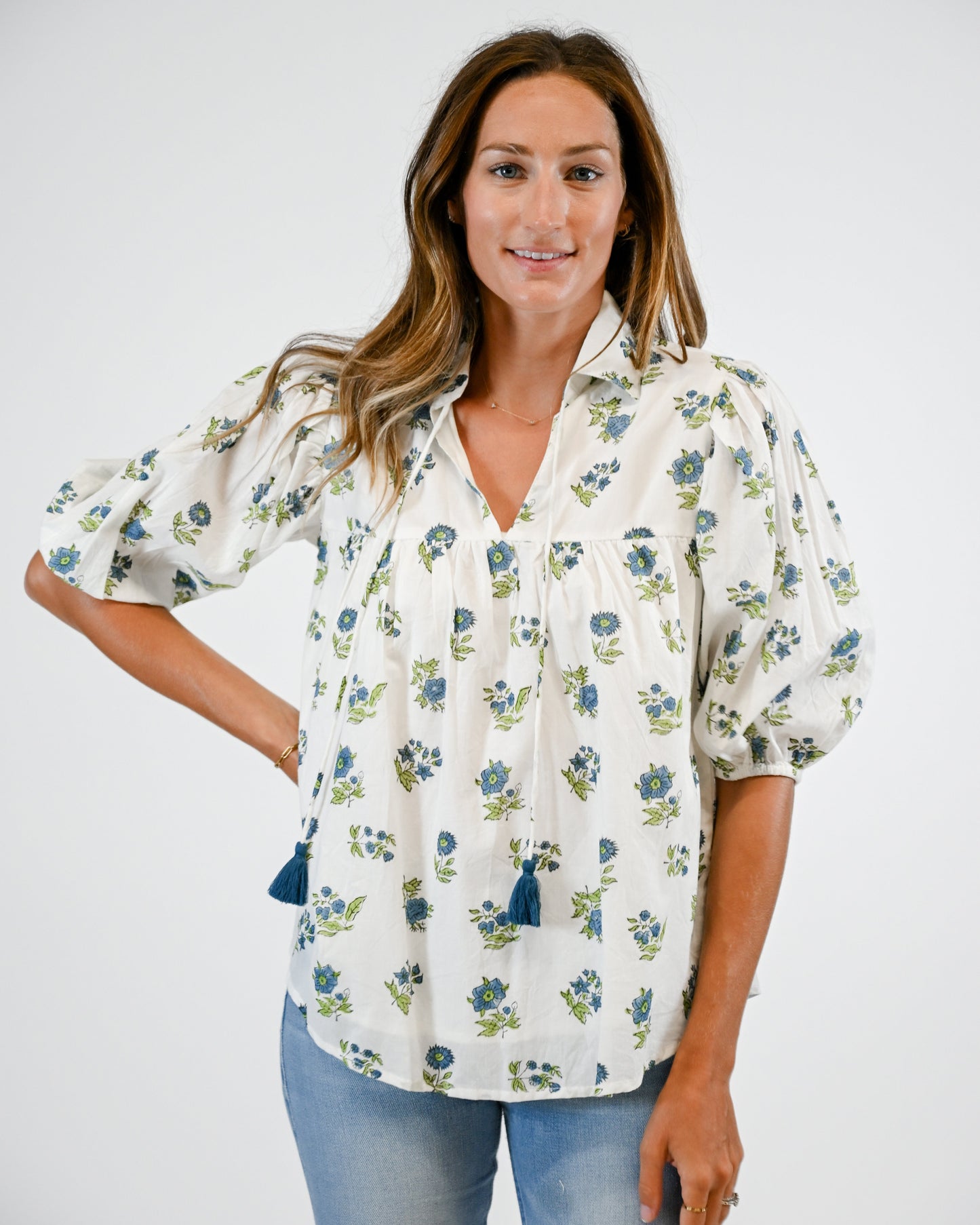 Woman wearing a floral blouse with puff sleeves on a white background