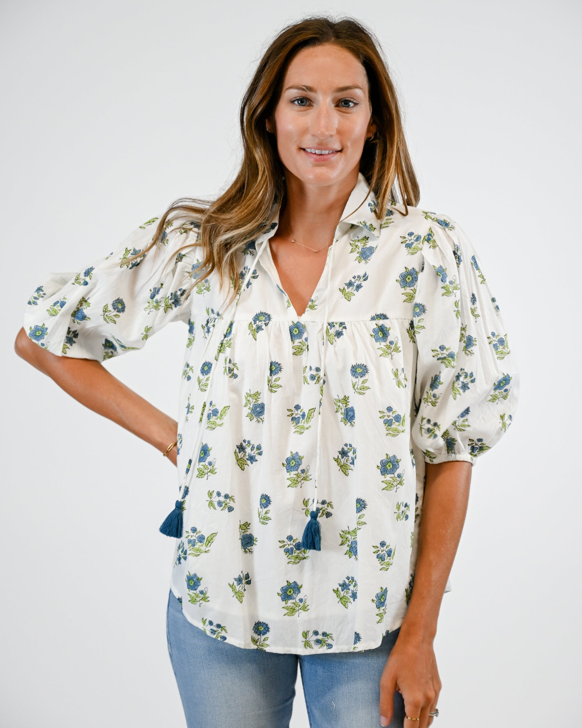 Woman wearing a floral blouse with puff sleeves on a white background
