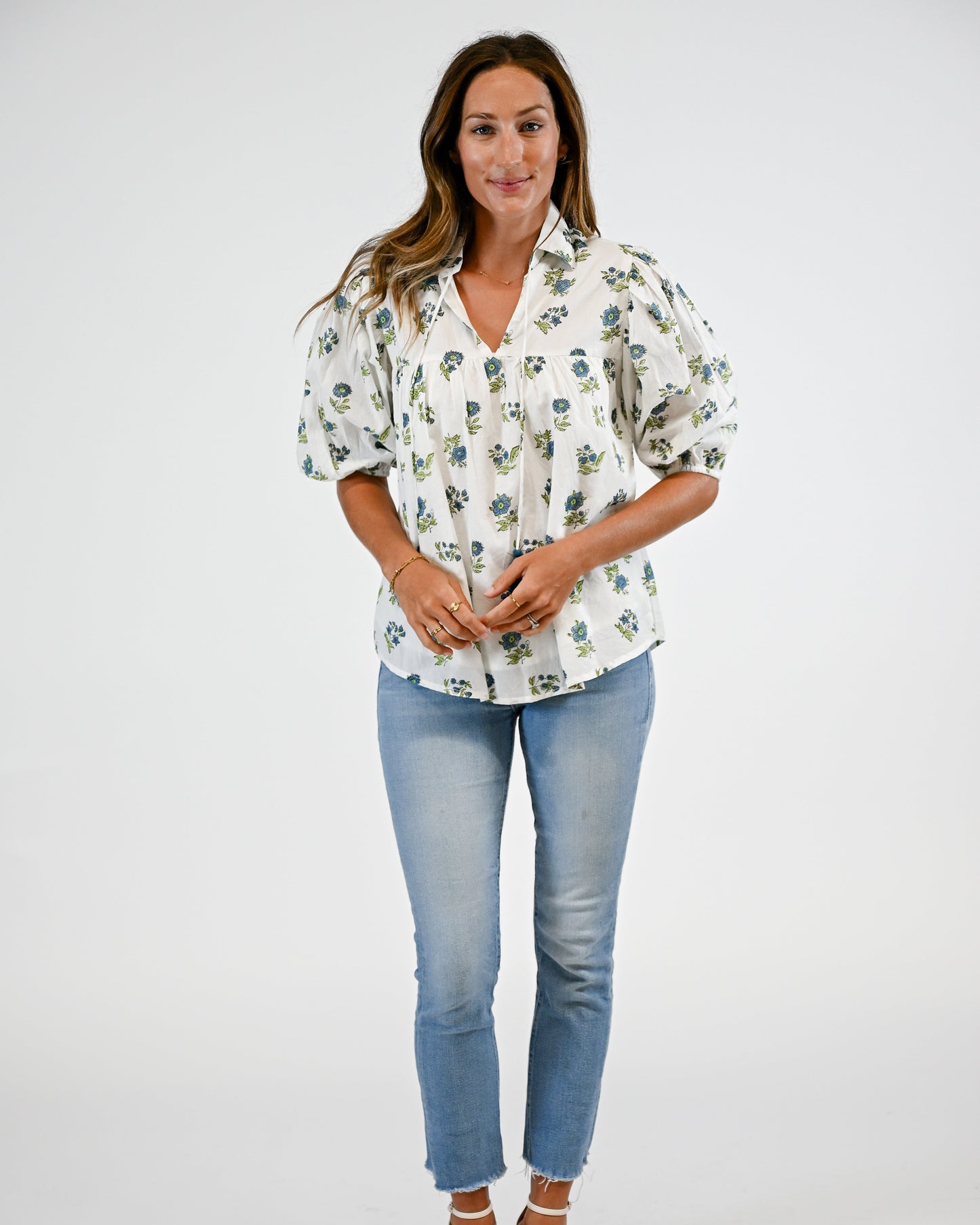 Woman wearing a floral blouse and blue jeans on a white background