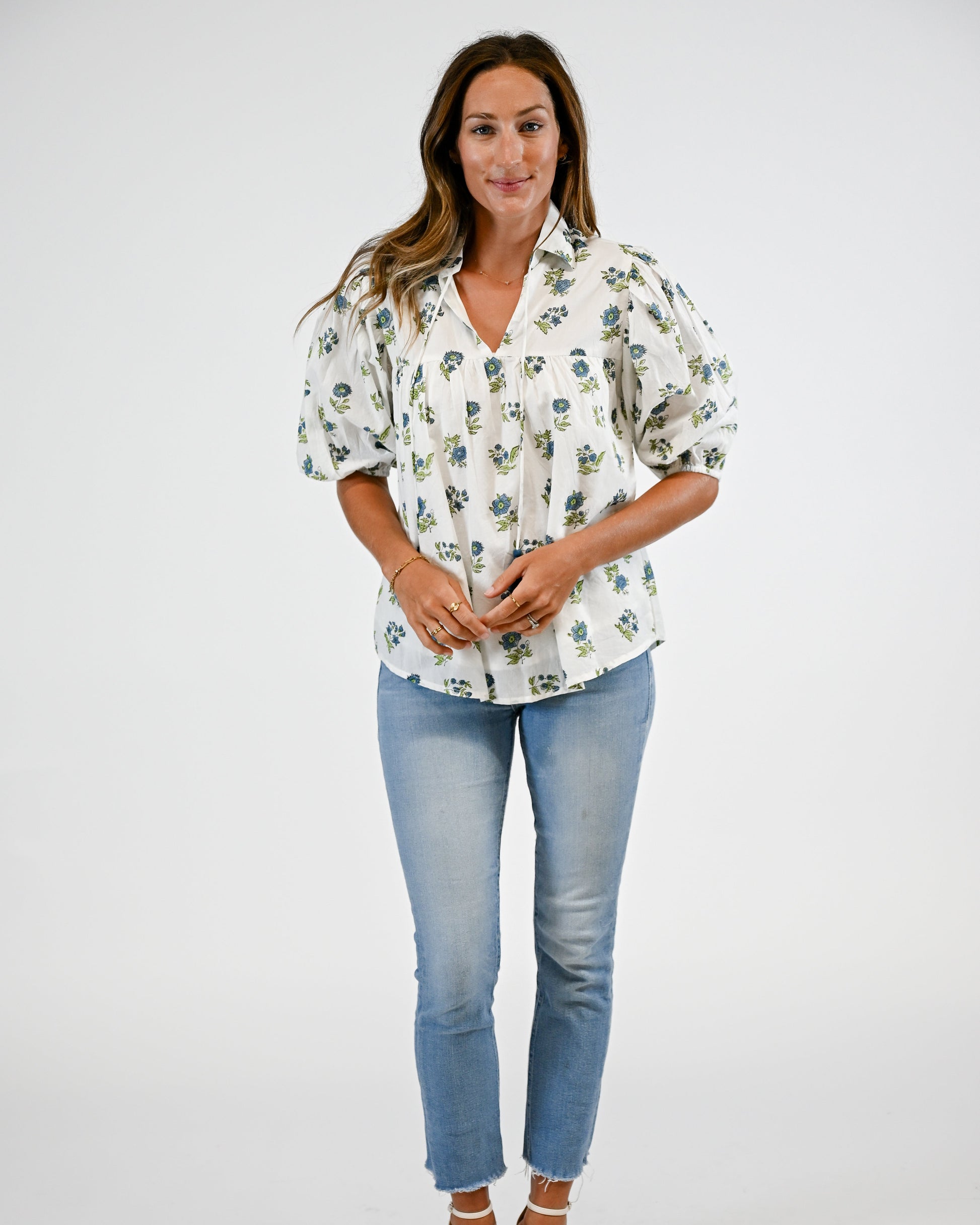 Woman wearing a floral blouse and blue jeans on a white background
