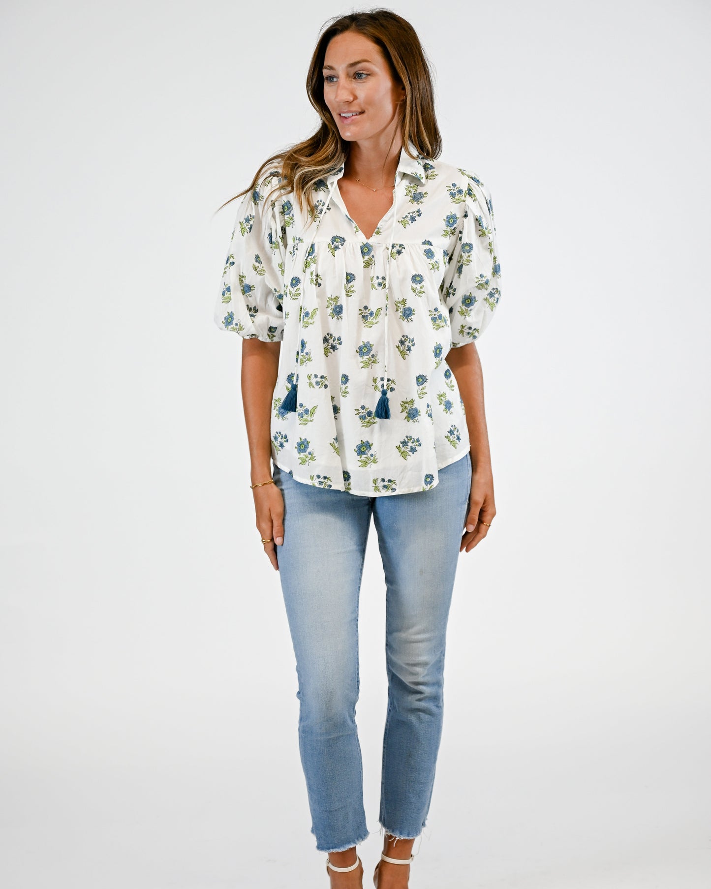Woman wearing a floral blouse and blue jeans on a white background
