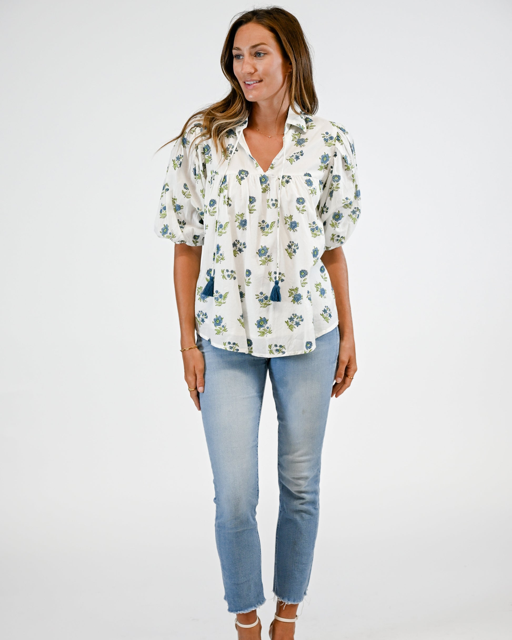 Woman wearing a floral blouse and blue jeans on a white background