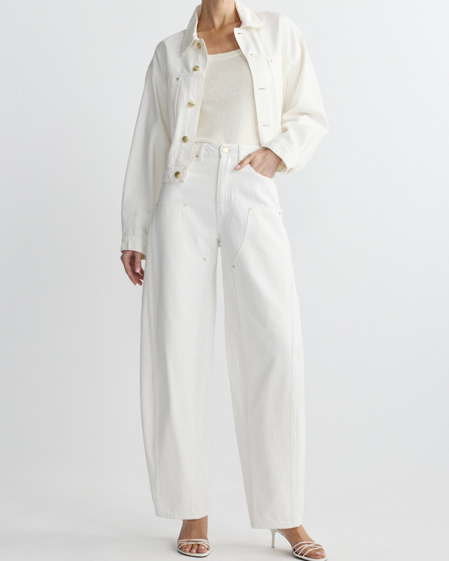 Person wearing a long white coat over a white shirt and pants on a plain background