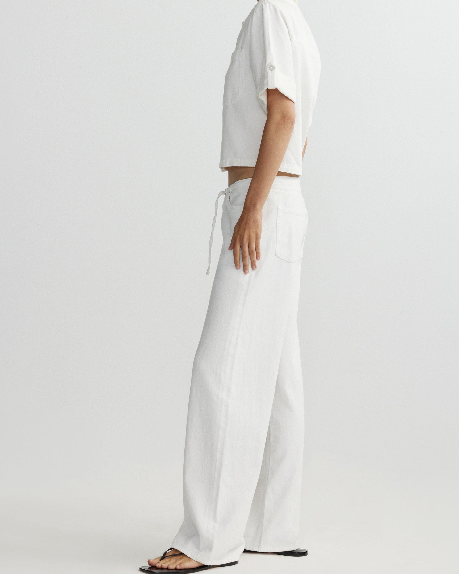 Person wearing a white outfit with wide-leg pants on a plain background