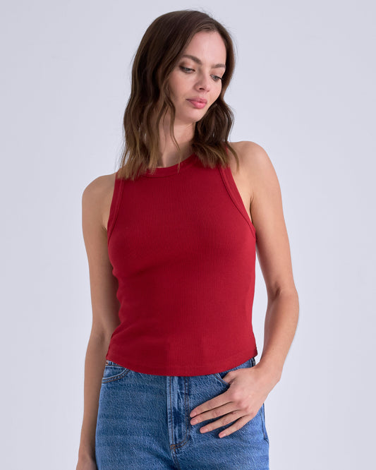 Woman wearing a red tank top and blue jeans against a white background