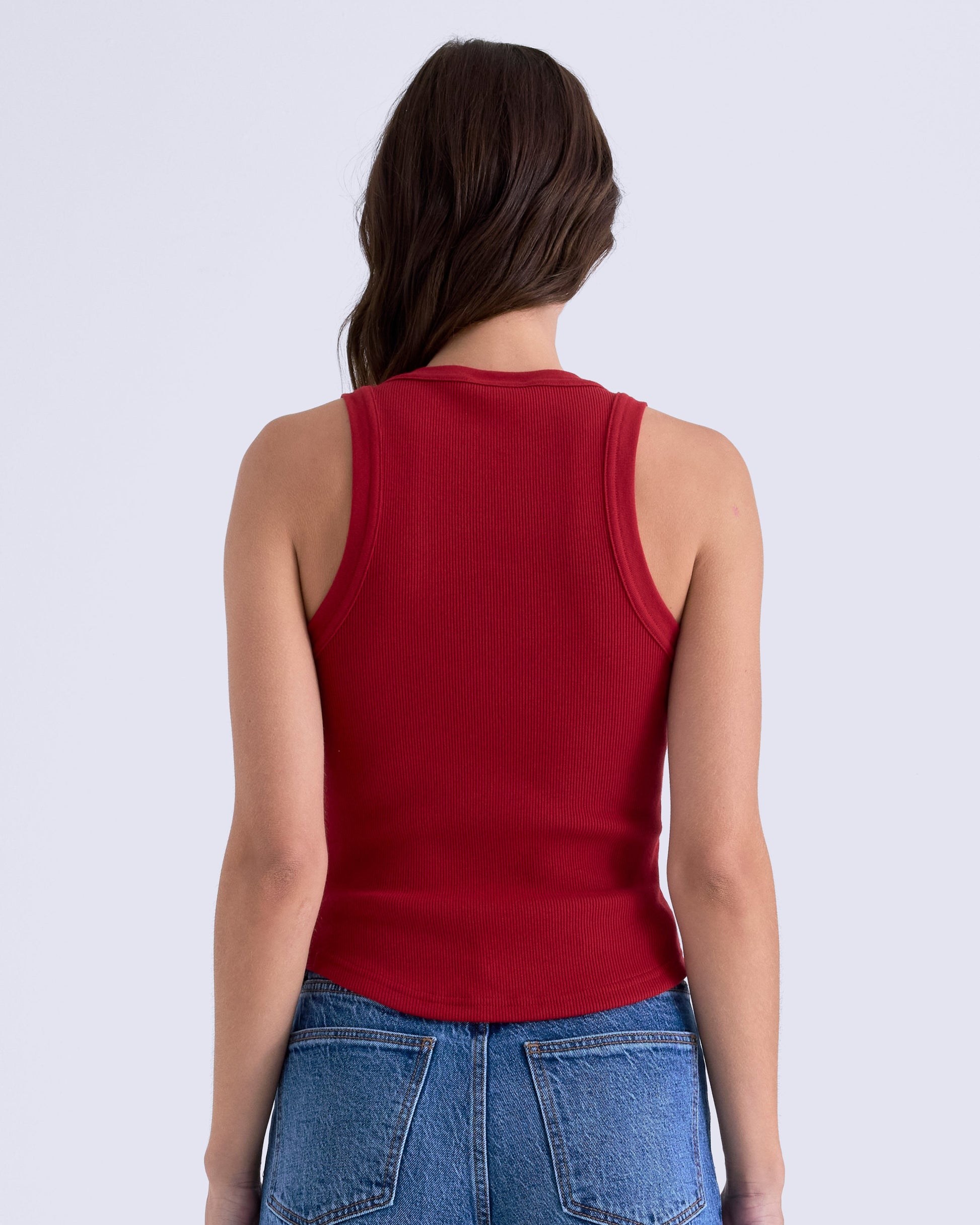 Person wearing a red tank top and blue jeans on a white background