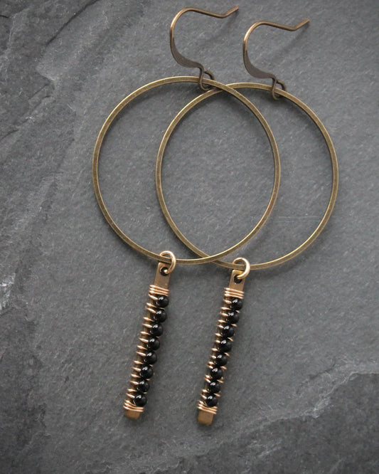 The Wild Balance Telluride Earring in the color Onyx resting on a stone