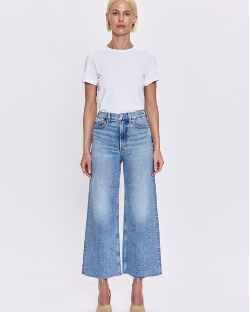 Person wearing a white t-shirt and blue wide-leg jeans on a white background