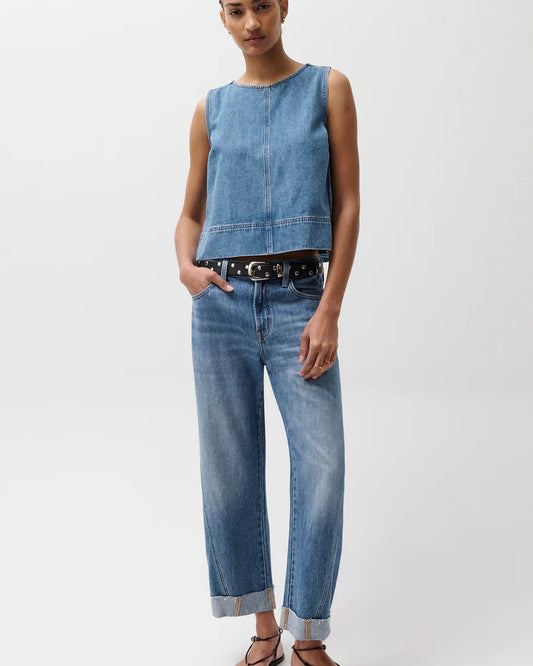 Model in denim top and jeans with a black belt in front of a white background