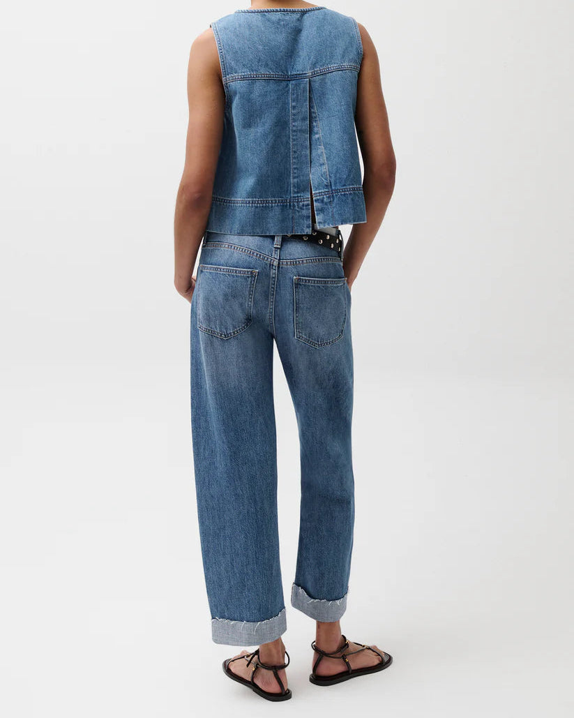 Model in a denim top with jeans standing in front of a white background