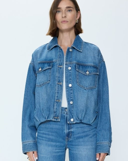 Woman wearing a blue denim jacket and jeans on a light gray background