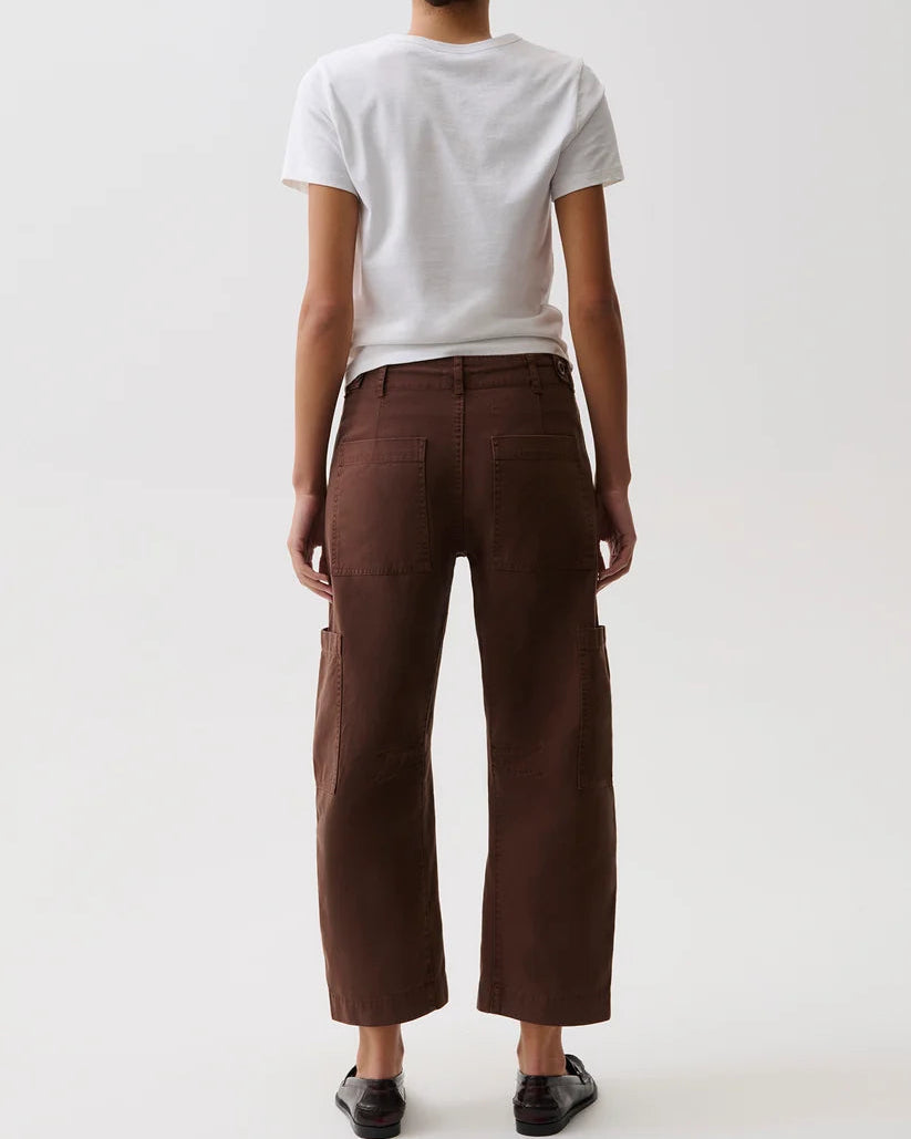 A model shown from the back wearing dark brown cropped cargo pants, a white t-shirt, and black shoes against a plain white studio background.